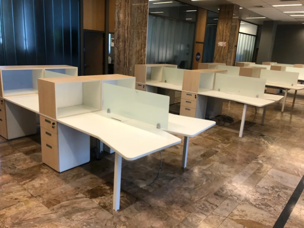 Puestos de trabajo blancos con divisores translúcidos y muebles de guardado.